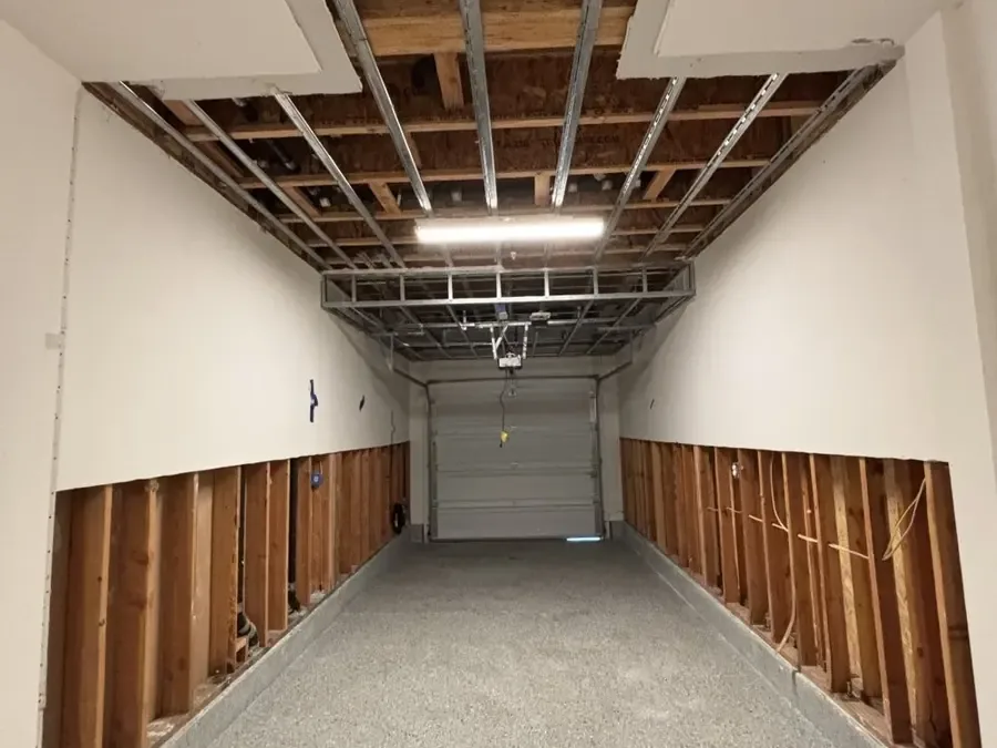 A garage with the lower drywall cut out on both walls after a water heater leak