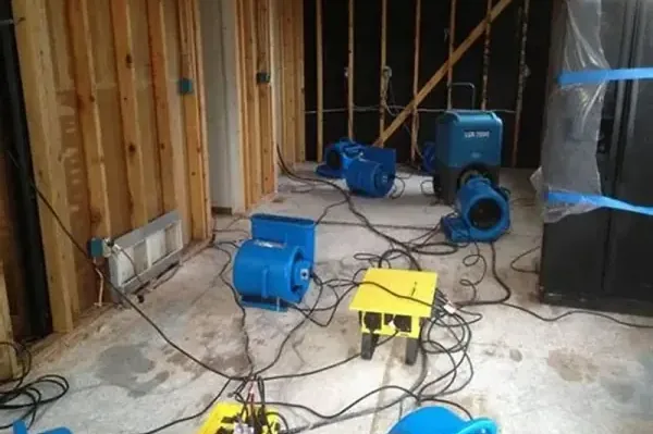 Air mover drying a garage floor where a water heater tank leaked