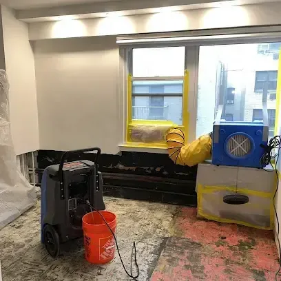 A dehumidifier and an air mover running together in a room where the flooring has been removed